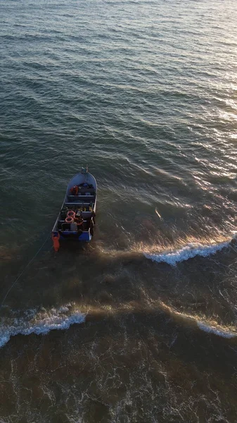 Costa da Caparica, Portekiz 22 Ağustos 2025: Balıkçıların teknelerini okyanus dalgalarına sürdükleri hava manzarası. Sahilde geleneksel balıkçılık sahnesi, takım çalışması ve deniz yaşamı yukarıdan ele geçirildi.