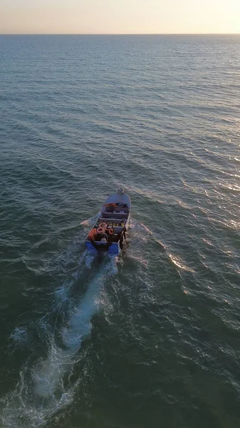 Costa da Caparica, Portekiz 22 Ağustos 2025: Balıkçıların teknelerini okyanus dalgalarına sürdükleri hava manzarası. Sahilde geleneksel balıkçılık sahnesi, takım çalışması ve deniz yaşamı yukarıdan ele geçirildi.