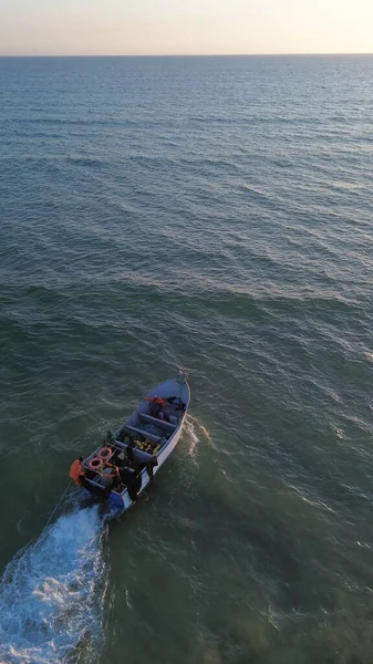 Costa da Caparica, Portekiz 22 Ağustos 2025: Balıkçıların teknelerini okyanus dalgalarına sürdükleri hava manzarası. Sahilde geleneksel balıkçılık sahnesi, takım çalışması ve deniz yaşamı yukarıdan ele geçirildi.