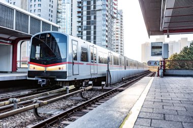 Şehirdeki bir açık hava istasyonuna hafif bir metro treni yaklaşıyor. Yatay yönelim.
