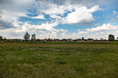 Kırsalda ekilmemiş bir tarlanın üzerinde kümülüs bulutları olan bir gökyüzü. Yatay yönelim.