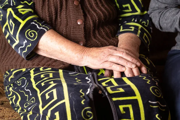 Hände einer älteren Frau in Strickpullover und Bademantel auf ihrem Schoß. Horizontale Orientierung. — Stockfoto