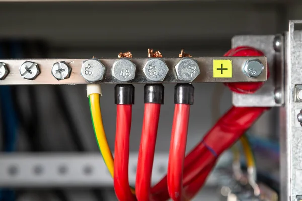 Pozitif otobüse bağlı elektrik kabloları. Kırmızı kablolar ve zemin. Yatay yönelim.