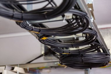 Kablo yönetimi. Çalışan kablolar, siyah kablolar bir bobine, bir daireye sarılmış. Kablolardan halkalar, tavandaki kablo merdiveni. Yatay yönelim.