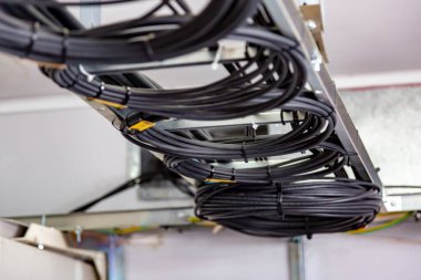 Kablo yönetimi. Çalışan kablolar, siyah kablolar bir bobine, bir daireye sarılmış. Kablolardan halkalar, tavandaki kablo merdiveni. Yatay yönelim.