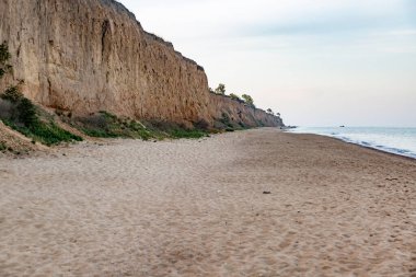 Sandy deniz kıyısı ve gölgede yüksek uçurum. Yatay yönelim.
