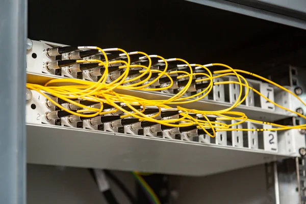 Багато жовтих волоконно-оптичних кабелів вставляються в комутатори в декількох рядах. Управління кабелем. Горизонтальна орієнтація . — стокове фото