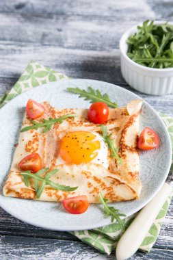 Yumurta, peynir, arugula yaprakları ve domates ile krep. 