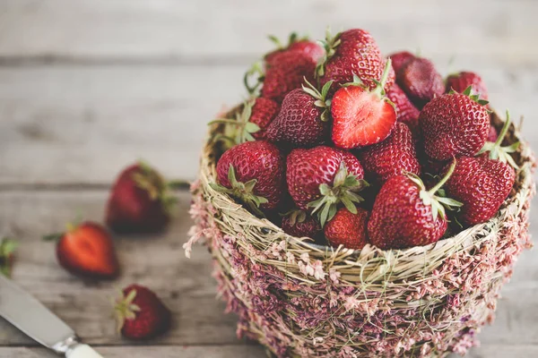 Fresas maduras en una hermosa canasta sobre un fondo de madera — Foto de Stock