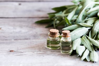 Ahşap masaüzerinde şişe de adaçayı yağı. Bir şişe temel oi