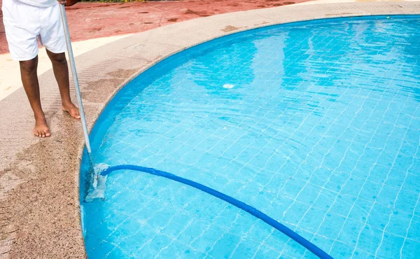 Man cleaning a swimming pool in summer. Cleaner of the swimming