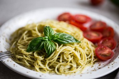 Spaghetti with homemade pesto sauce, basil leaves and  tomatoes/