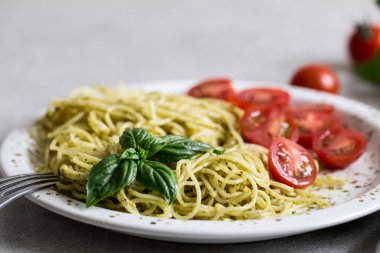 Spaghetti with homemade pesto sauce, basil leaves and  tomatoes/
