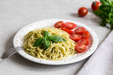 Spaghetti with homemade pesto sauce, basil leaves and  tomatoes/