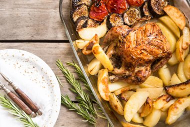 Fırında patates, patlıcan ve kiraz domates ile bütün tavuk.