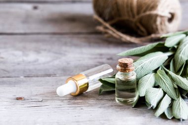 Ahşap masaüzerinde şişe de adaçayı yağı. Bir şişe temel oi