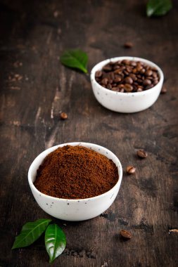 Kahve çekirdekleri ve kahve kaselerinde kahve ağacı yaprağı var.