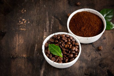 Kahve çekirdekleri ve kahve kaselerinde kahve ağacı yaprağı var.