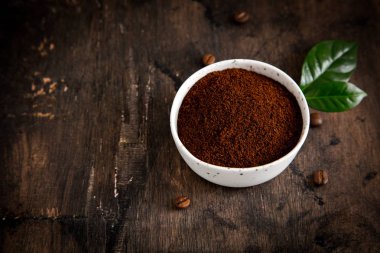 Kahve çekirdekleri ve kahve kaselerinde kahve ağacı yaprağı var.