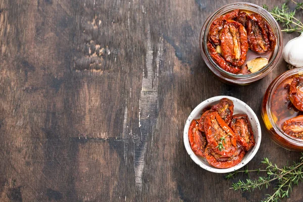 Sun dried tomatoes with olive oil in a jar on wooden background/ — Stockfoto