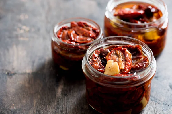 Sun dried tomatoes with olive oil in a jar on wooden background/ — Stockfoto