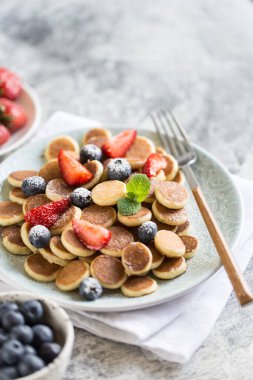 Kahvaltıda minik gözlemeler. Böğürtlenli tahıllı gözleme, gri arka planda çilek. Moda yemekler. Seçici odak