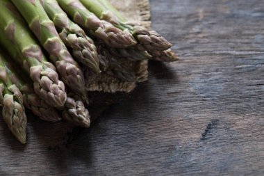 Yeşil kuşkonmaz. Koyu ahşap bir arka planda bir sürü yeşil kuşkonmaz.