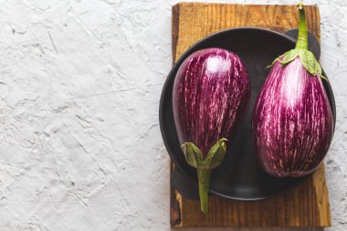 Beton bir arka planda kesme tahtasındaki taze patlıcanlar.