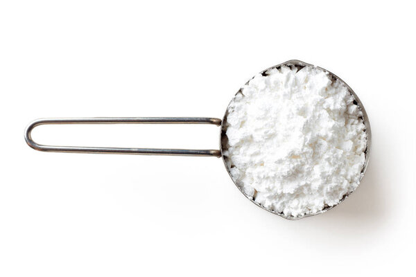 Measuring scoop with powder sugar isolated on white background, top view