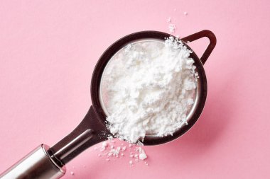 Süzgeç ile toz şeker pembe arka plan, üstten görünüm