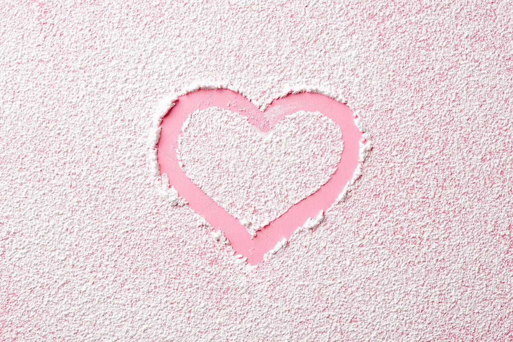 Pink heart in white powder sugar, top view
