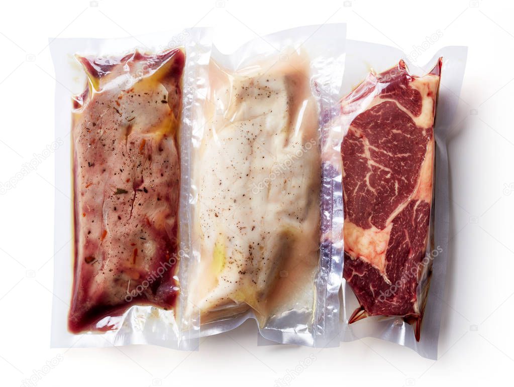 Duck breast, chicken breast and beef steak vacuum sealed ready for sous vide cooking, isolated on white background, top view