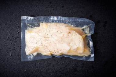 Chicken breast vacuum sealed ready for sous vide cooking on black background, top view clipart