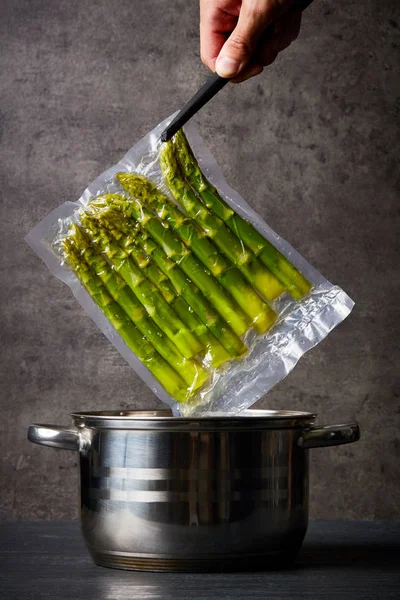 Main Tenant Des Asperges Fraîches Dans Sac Sous Vide Sur — Photo