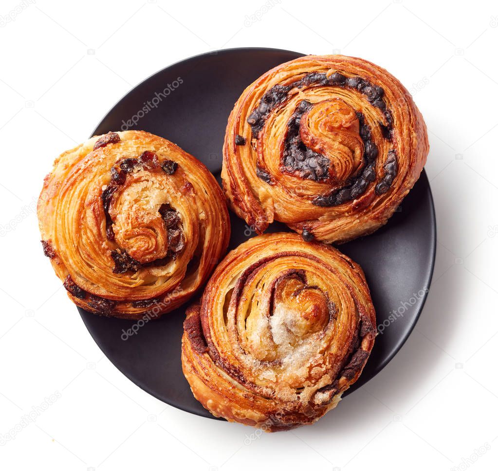 Freshly baked sweet buns on black plate isolated on white background, top view