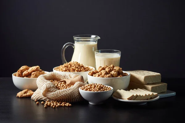 Soy products: soy beans, soy milk, tofu and soya chunks on black background