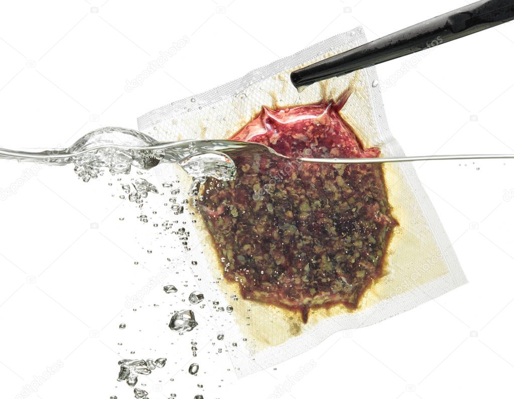 Burger meat in vacuum bag in water; isolated on white