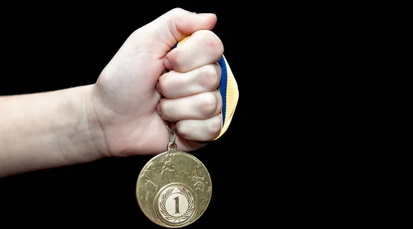 Mulher mão segurando medalha de ouro contra fundo preto. Conceito de prêmio e vitória — Fotografia de Stock