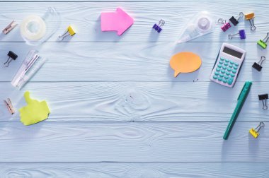 Ofis, iş, eğitim natürmort kavramı mavi ahşap zemin üzerinde. Üstten görünüm parlak renkli Kırtasiye ile ahşap masaüstü. İleti örneği, düz dizi yatıyordu.