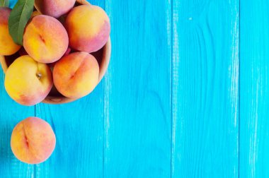 Mavi ahşap arka plan üzerinde ahşap bir kase taze olgun şeftali. Taze meyve arka plan. Yaz meyve.