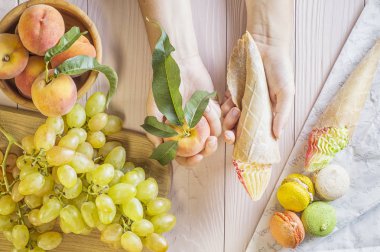 Eller onları arasında bir seçim yapma bir pasta ve şeftali, tutan genç bir kadın. Tatlı ve meyveler arasında bir seçim yapma kadın. Sağlıklı vs sağlıksız yiyecek. üstten görünüm, düz yatıyordu.