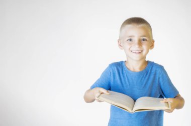 Kitap ile küçük gülümseyen öğrenci portresi. Neşeli gülümseyen küçük çocuk. Kameraya bakıyor. Okul kavramı.