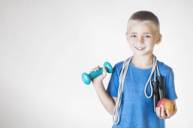 Kırmızı elma ve halter kaldırma ip atlama ile çocuk gülümseyen mutlu portre portre. Kameraya bakıyor. Sağlıklı yaşam kavramı. Spor ve aktiviteler çocuklar için.