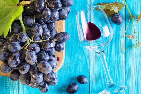 葡萄とワイングラス青い木製のテーブル 平面図 新鮮な熟した赤ブドウの枝 青葡萄の枝と美しい背景 暗い赤ワイン ブドウ — ストック写真