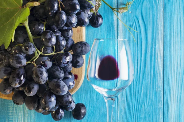 葡萄とワイングラス青い木製のテーブル 平面図 新鮮な熟した赤ブドウの枝 青葡萄の枝と美しい背景 暗い赤ワイン ブドウ — ストック写真
