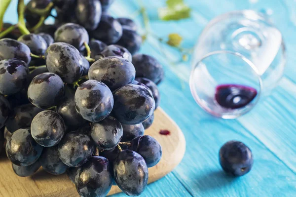 葡萄とワイングラス青い木製のテーブル 新鮮な熟した赤ブドウの枝 青葡萄の枝と美しい背景 暗い赤ワイン ブドウ — ストック写真