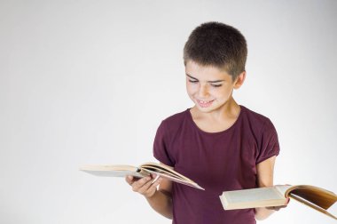 Çocuk tutan iki açık kitap gülümseyen mutlu portre. Genç gülümsüyor ve elinde tutar kitaplar bakar. Çocuk holding kitaplar. Okula geri kavramı.