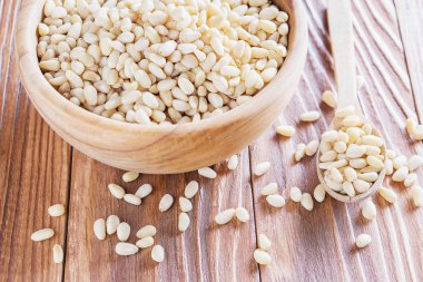 Sedir fındık veya çam fıstığı rustik ahşap zemin üzerinde. Ahşap kase ve kaşık soyulmuş çam fıstığı.