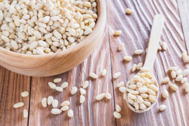 Sedir fındık veya çam fıstığı rustik ahşap zemin üzerinde. Ahşap kase ve kaşık soyulmuş çam fıstığı.