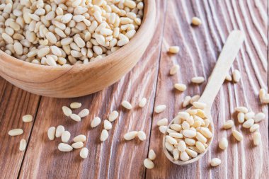 Sedir fındık veya çam fıstığı rustik ahşap zemin üzerinde. Ahşap kase ve kaşık soyulmuş çam fıstığı.